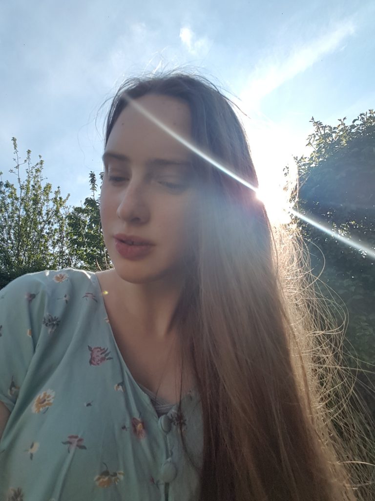 Selfie of Sakara, she's looking to the side and seems calm, the sun is visible to the right of the picture.