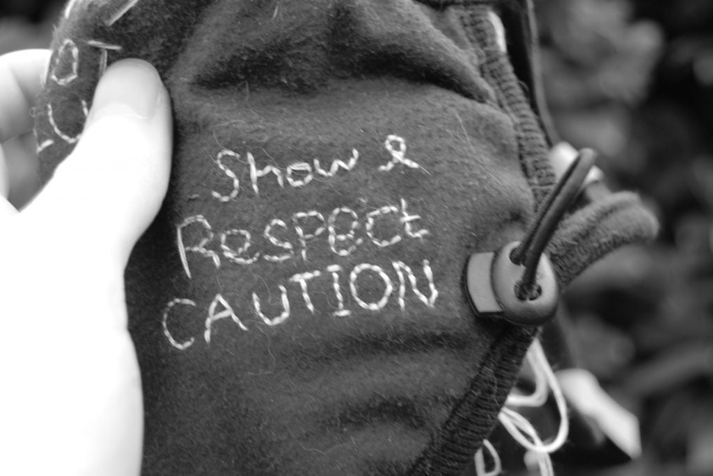 A black and white photograph of text on the mask, saying "show and respect caution".