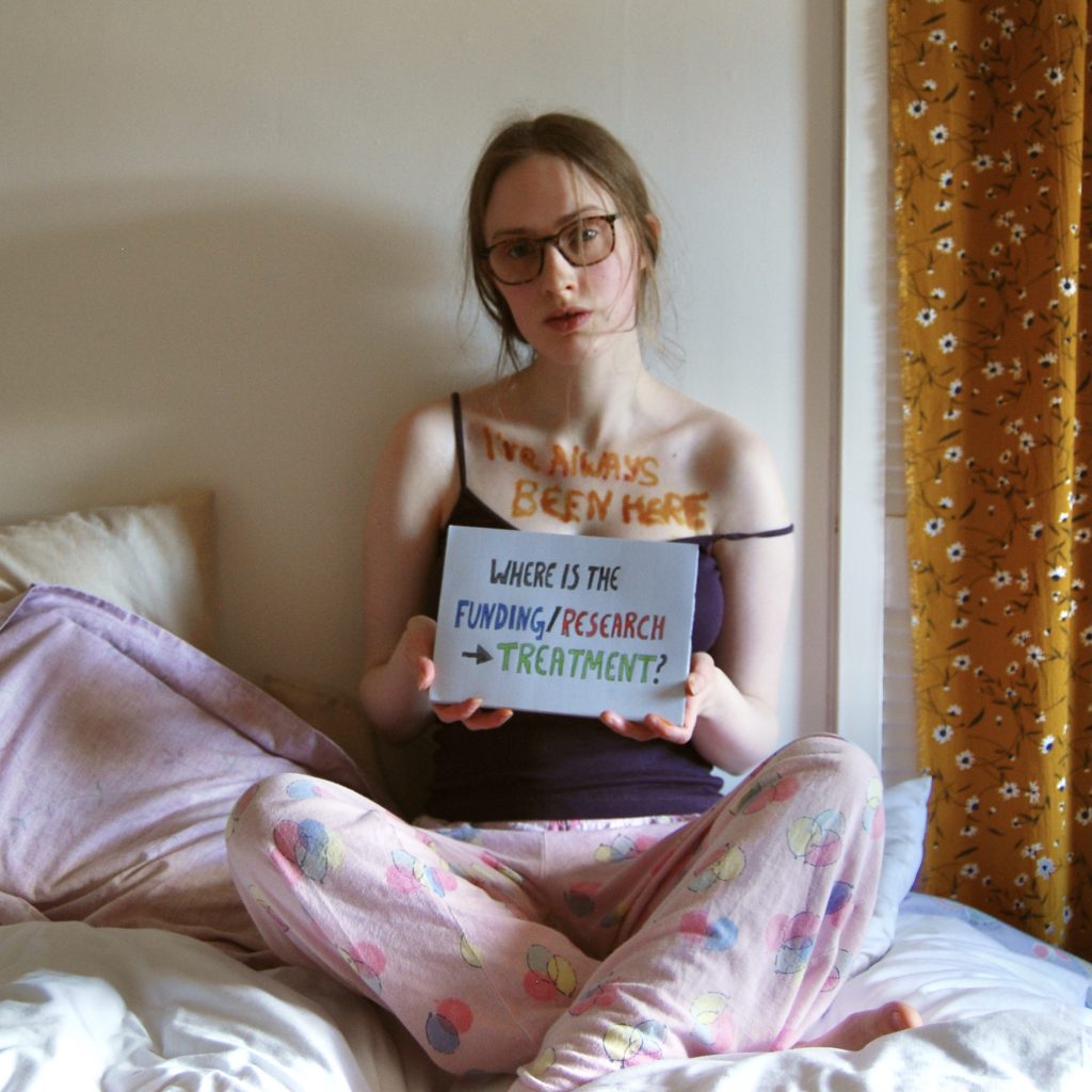 Sakara is now holding a sign asking "where are the funding and research leading to treatment?"