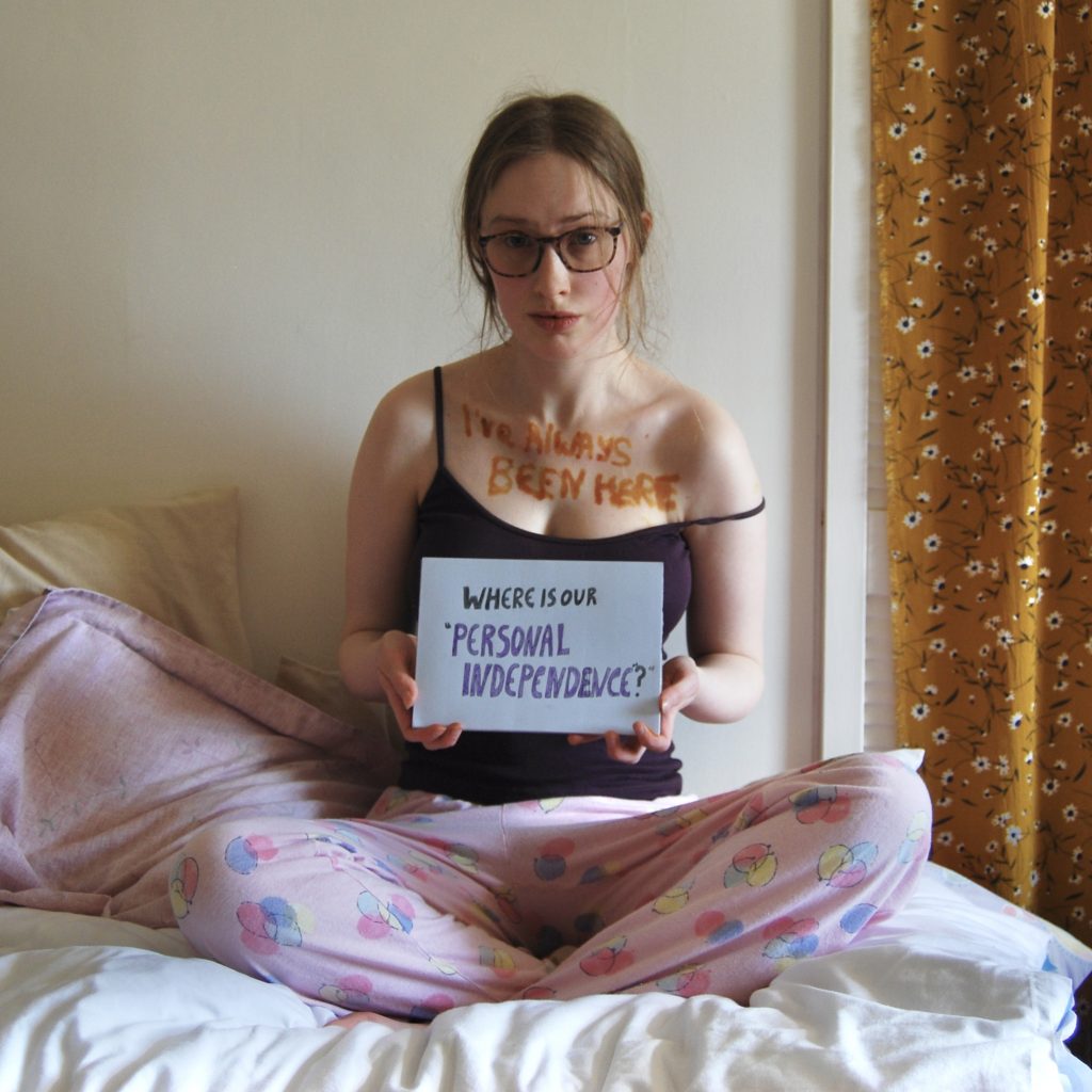 Sakara is raising her eyebrows and smirking slightly, holding a sign asking "where is our personal independence?"