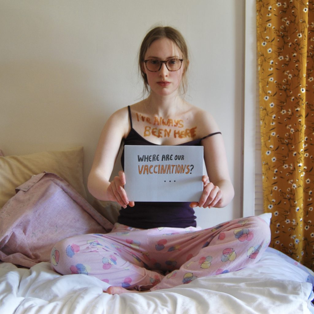 Sakara holds forward another sign asking where our vaccinations are.