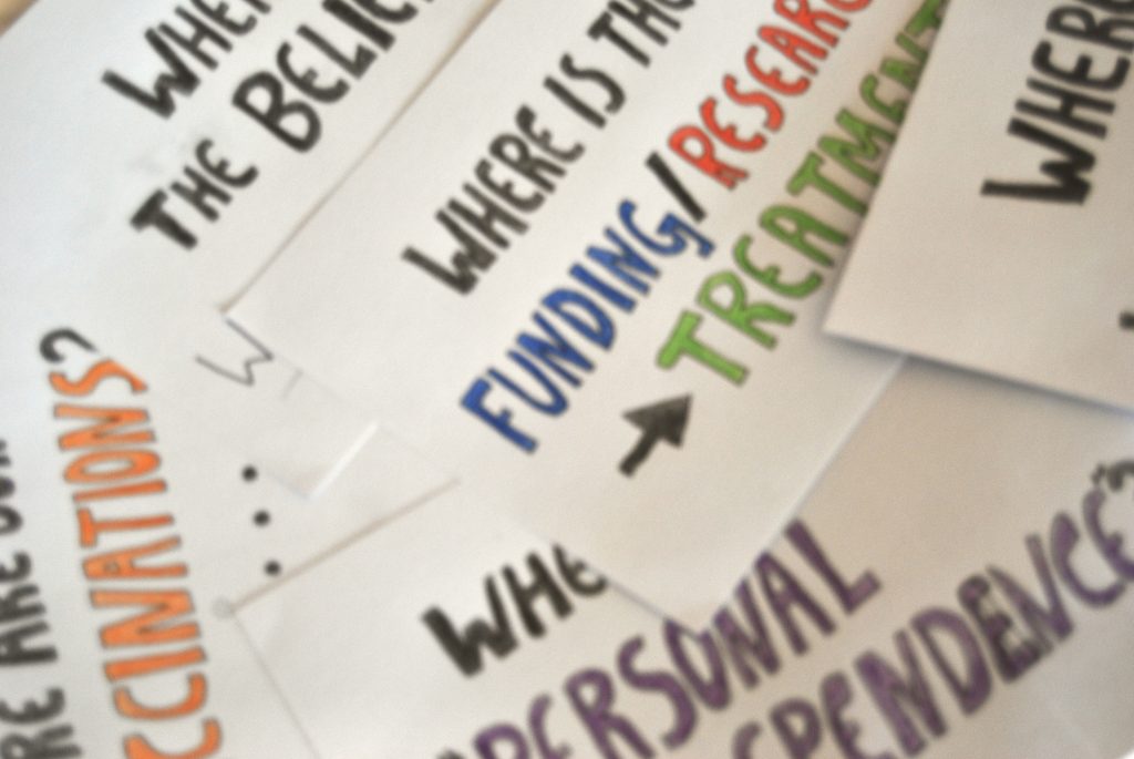 Handwritten signs are laying down, overlapping each other on a flat surface.