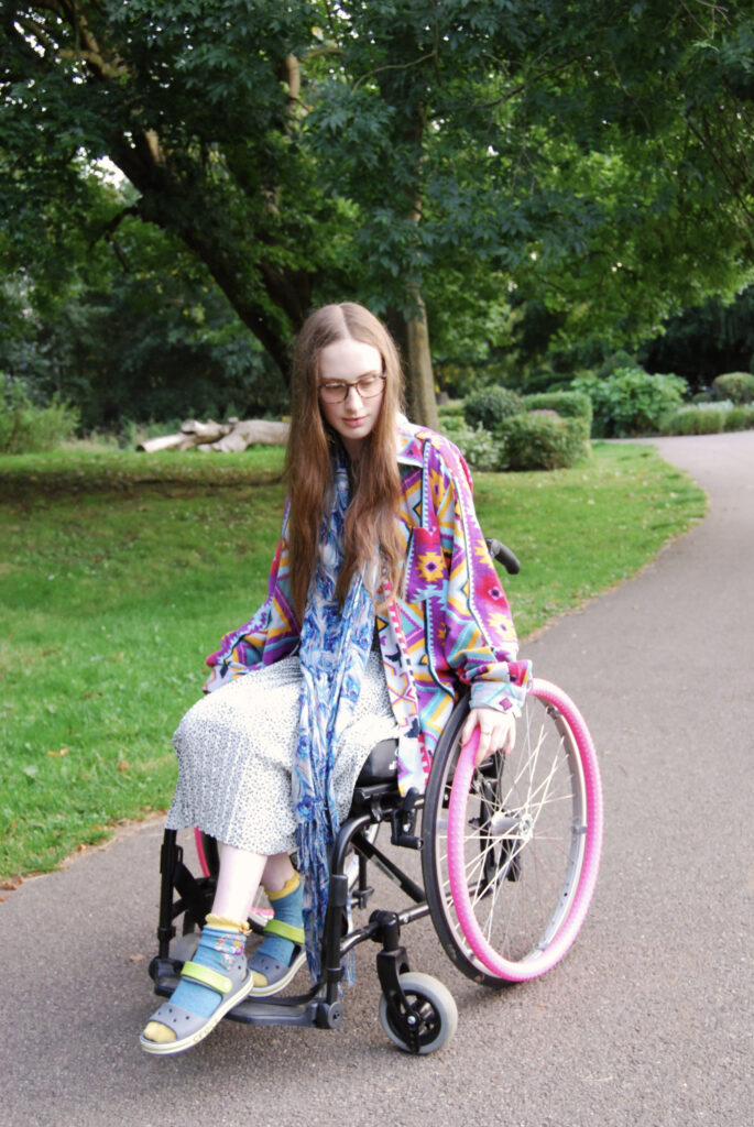 Sakara sits in her wheelchair wearing colourful clothes