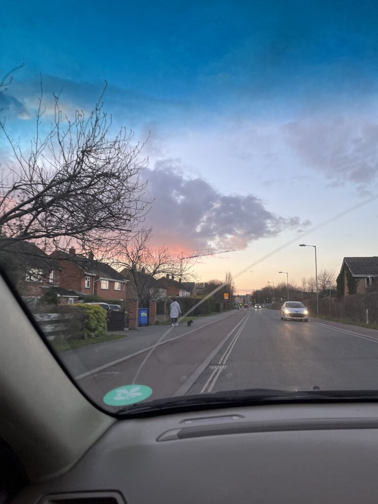 A residential street viewed from inside a car.