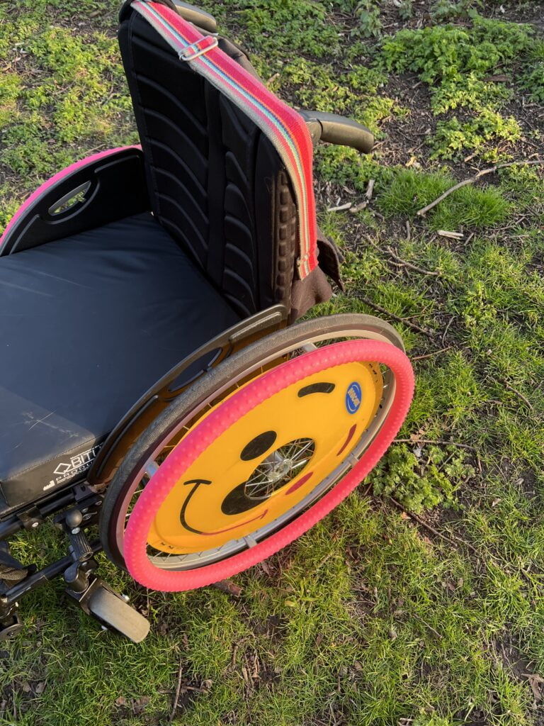 Side shot of a wheelchair with smiley face wheel cover.