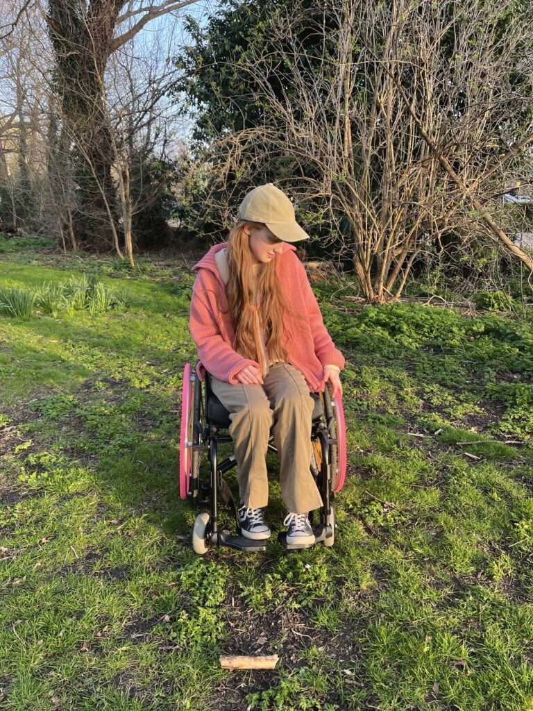 Sakara fiddles with her wheelchair rim.